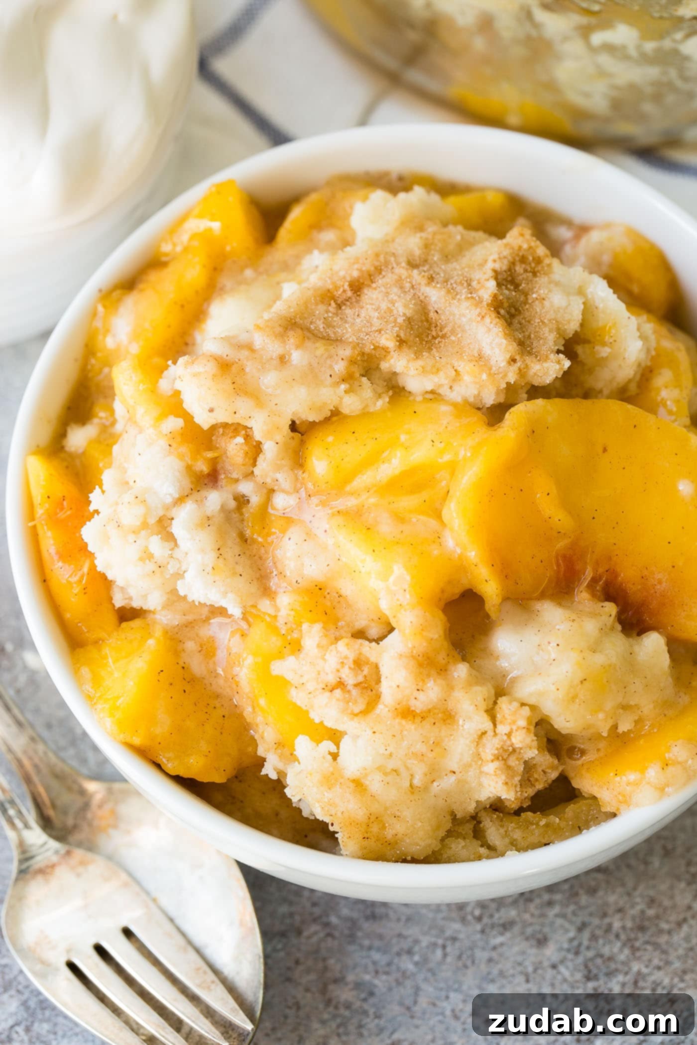 Easy Instant Pot Peach Cobbler with Cake Mix A close-up shot of a bowl of peach cobbler, highlighting the golden cake mix topping and juicy peaches.
