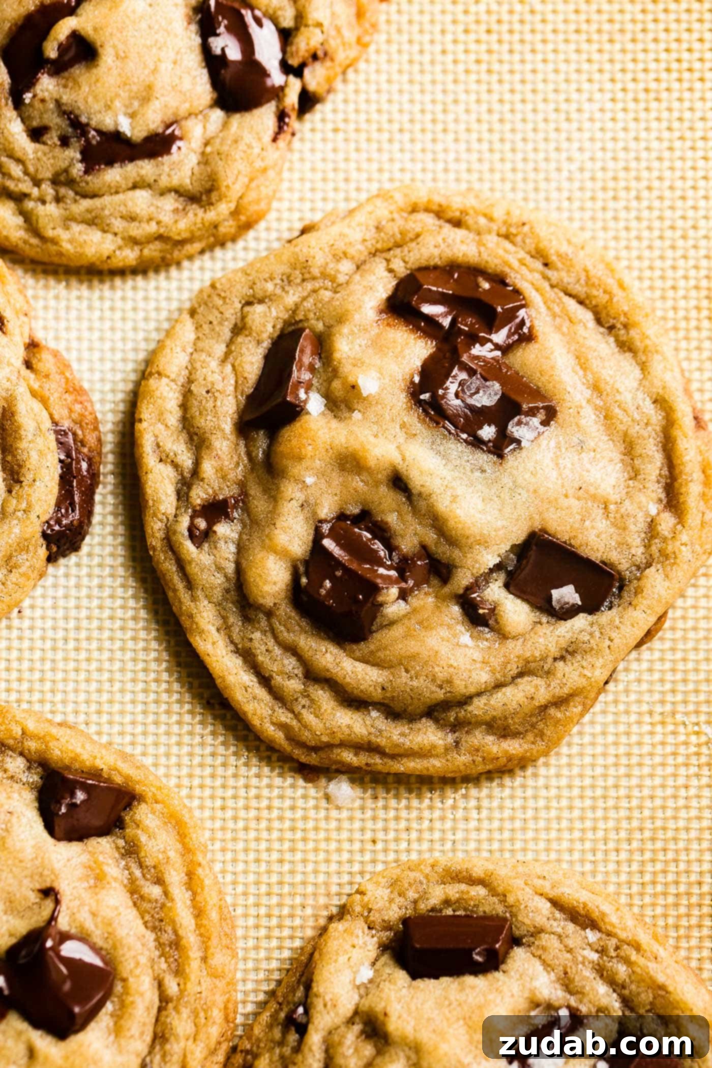 Chocolate Lover's Ultimate Chocolate Chip Cookies 7 A trio of delicious chocolate chip cookies, stacked and showcasing their perfect golden-brown exterior and soft, inviting texture.