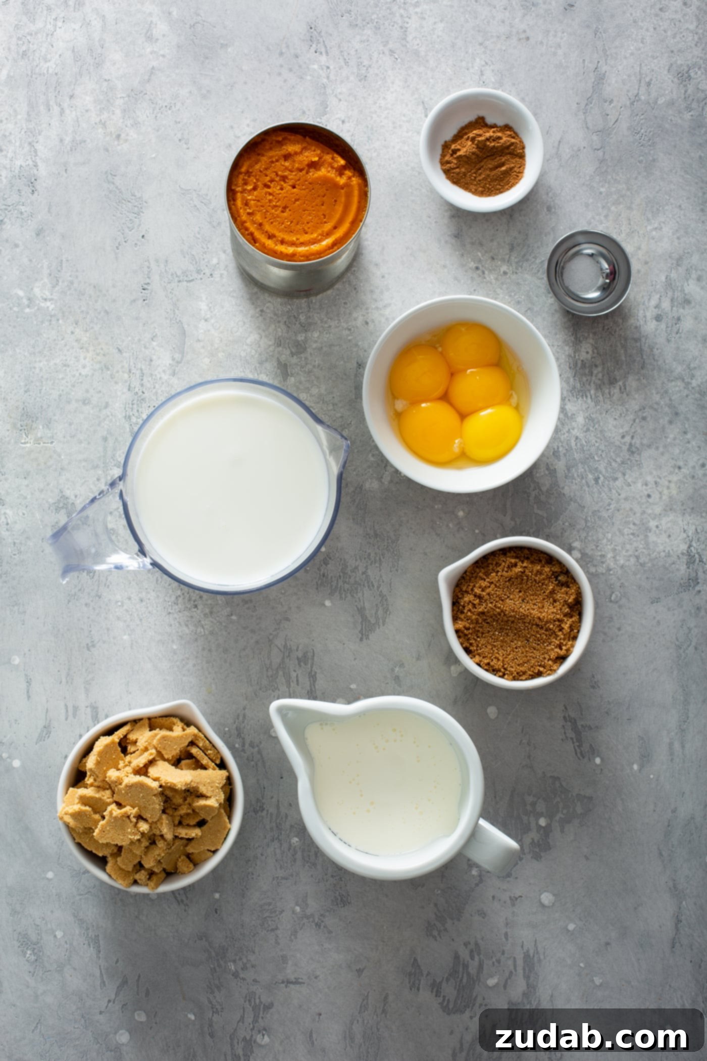 The Creamiest Pumpkin Ice Cream Small containers filled with the ingredients for pumpkin ice cream. There is a measuring cup of milk, small bowls of egg yolks, cinnamon, brown sugar, pumpkin and creamer filled with heavy cream.