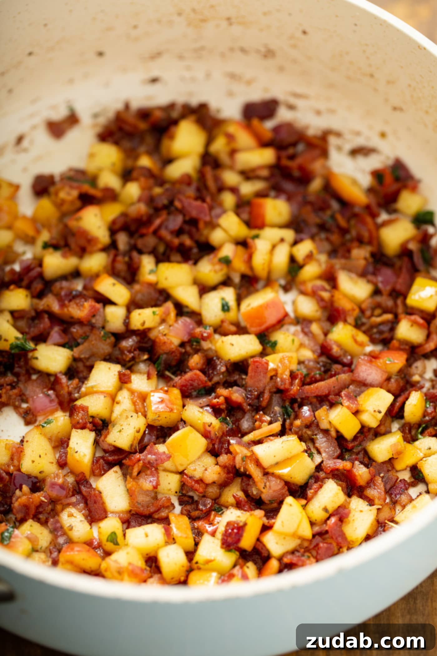 Maple Mustard Apple Chicken Burgers A large skillet brimming with a savory and aromatic mixture of cooked bacon, tender apples, caramelized onions, and a medley of spices and herbs. The ingredients are perfectly combined, ready to be incorporated into the chicken burger patties.