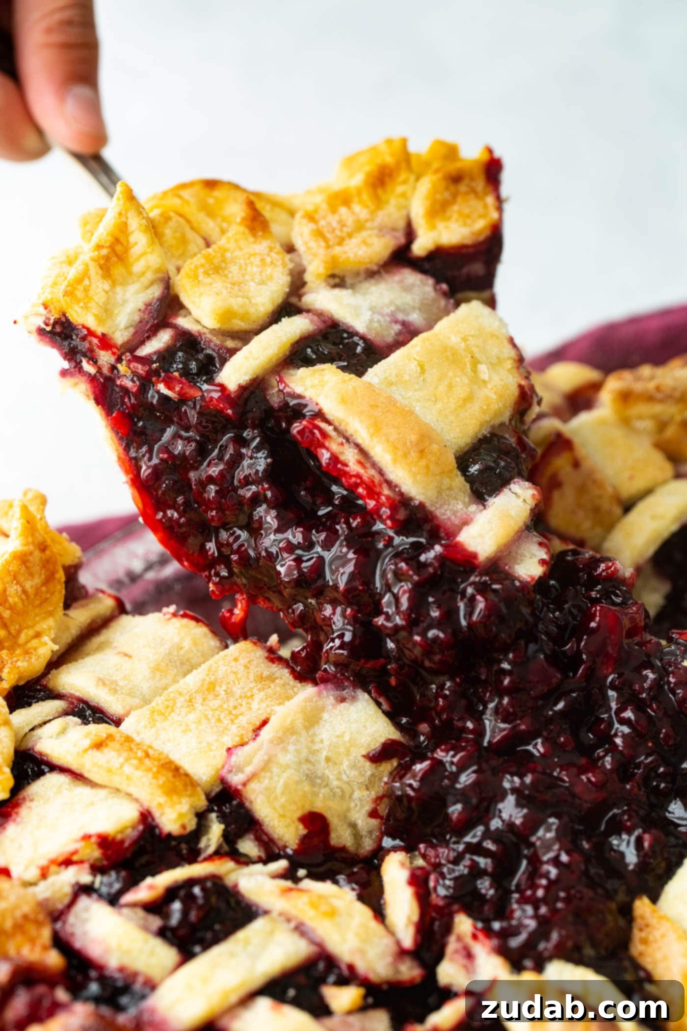 Blackberry Marionberry Pie Perfection 5 A mouth-watering slice of Marionberry pie being carefully lifted from the pie dish, revealing its rich, bubbly filling.