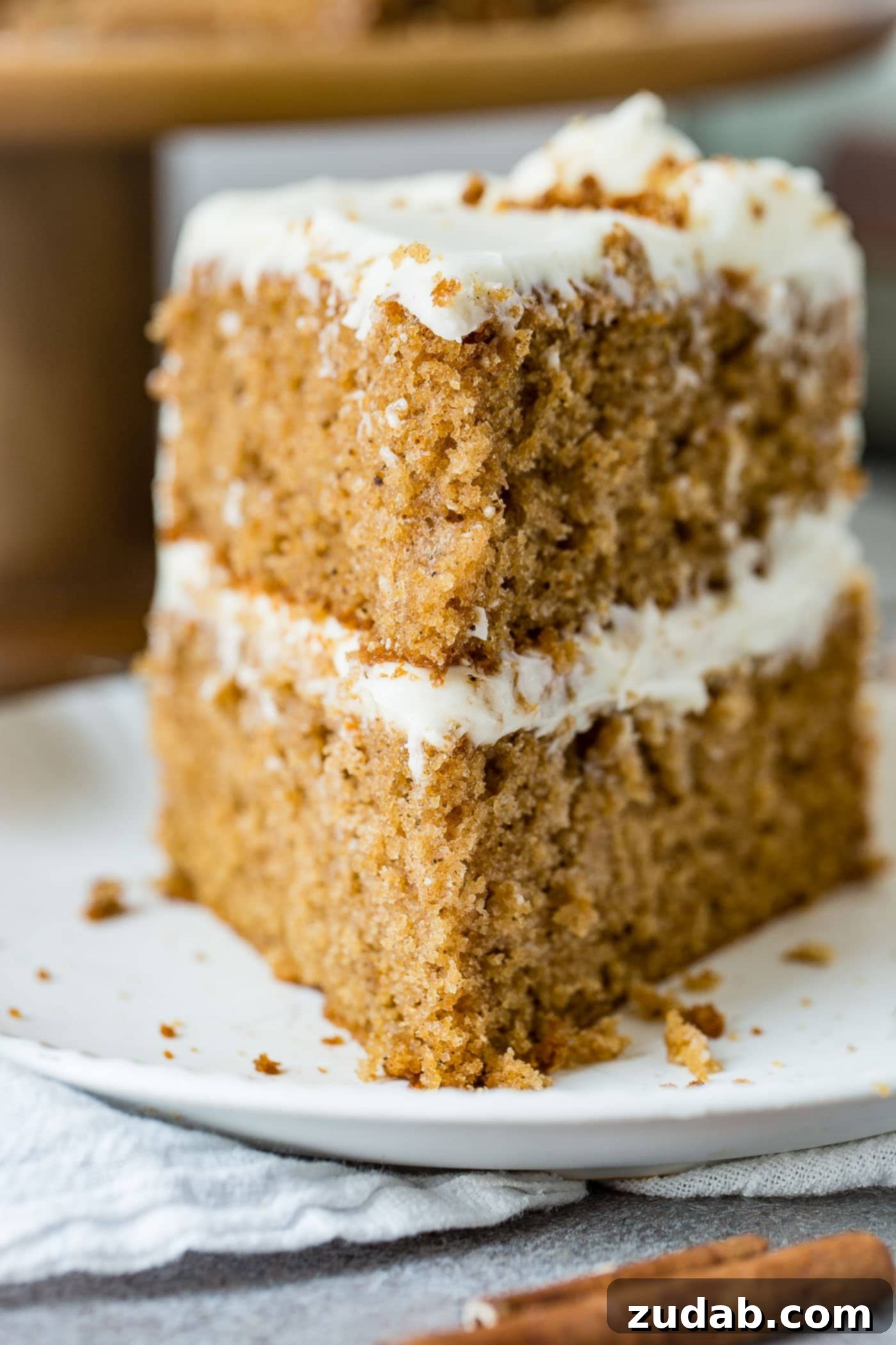 Cross-Section of Spice Cake A beautiful cross-section of a two-layer spice cake, revealing the moist cake texture and generous layers of cream cheese frosting.