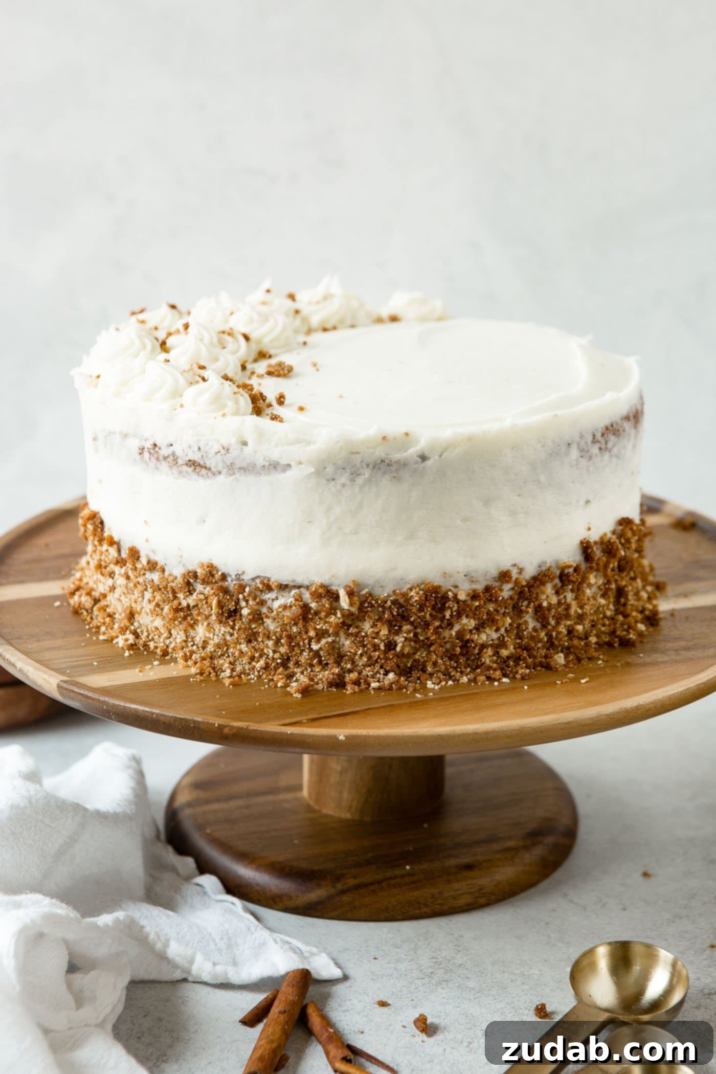 Whole Frosted Spice Cake A beautifully frosted two-layer spice cake resting on a pristine white cake stand. The creamy white frosting contrasts elegantly with the warm tones of the cake.