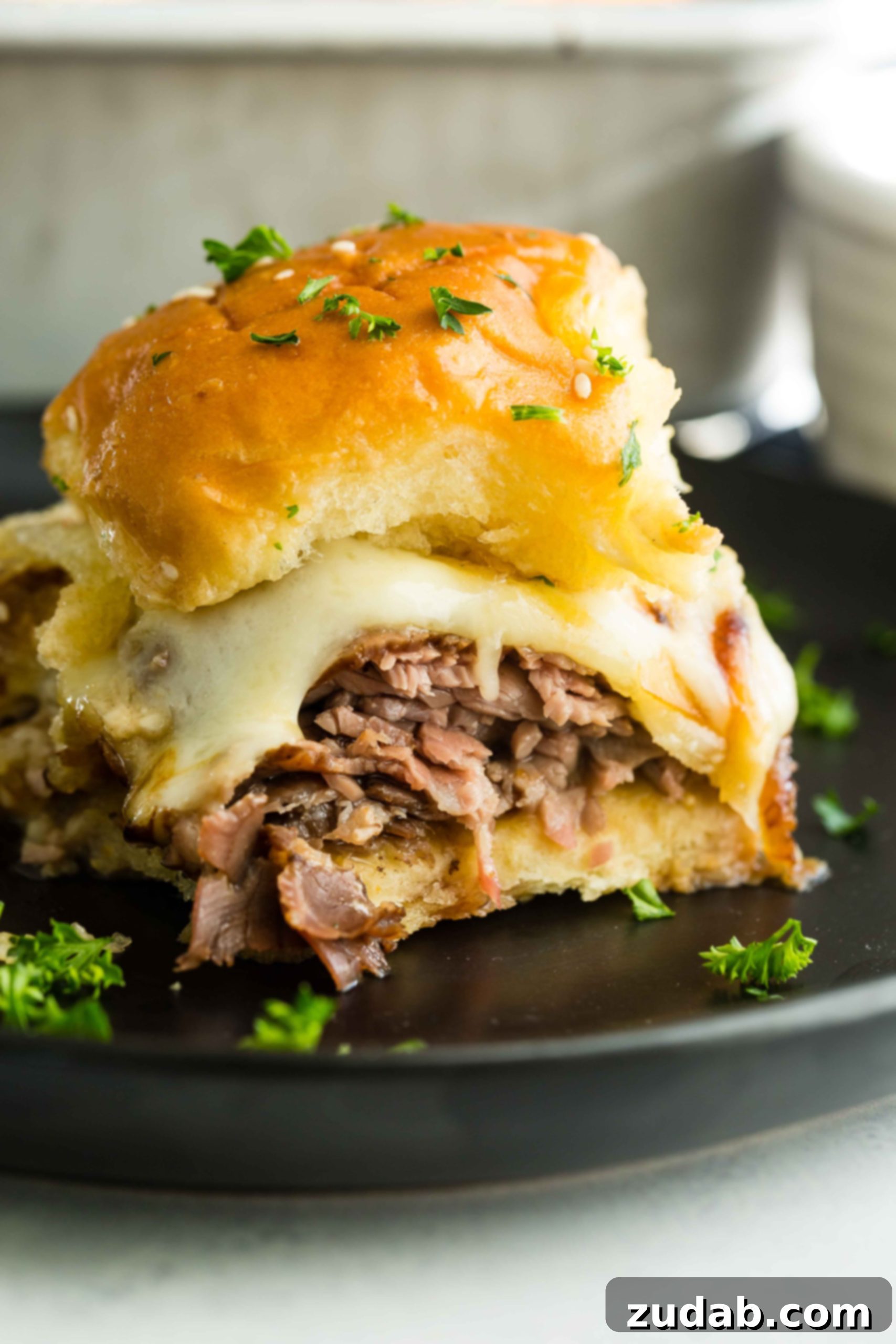 French Dip Sliders A photo of a single french dip slider on a black plate.