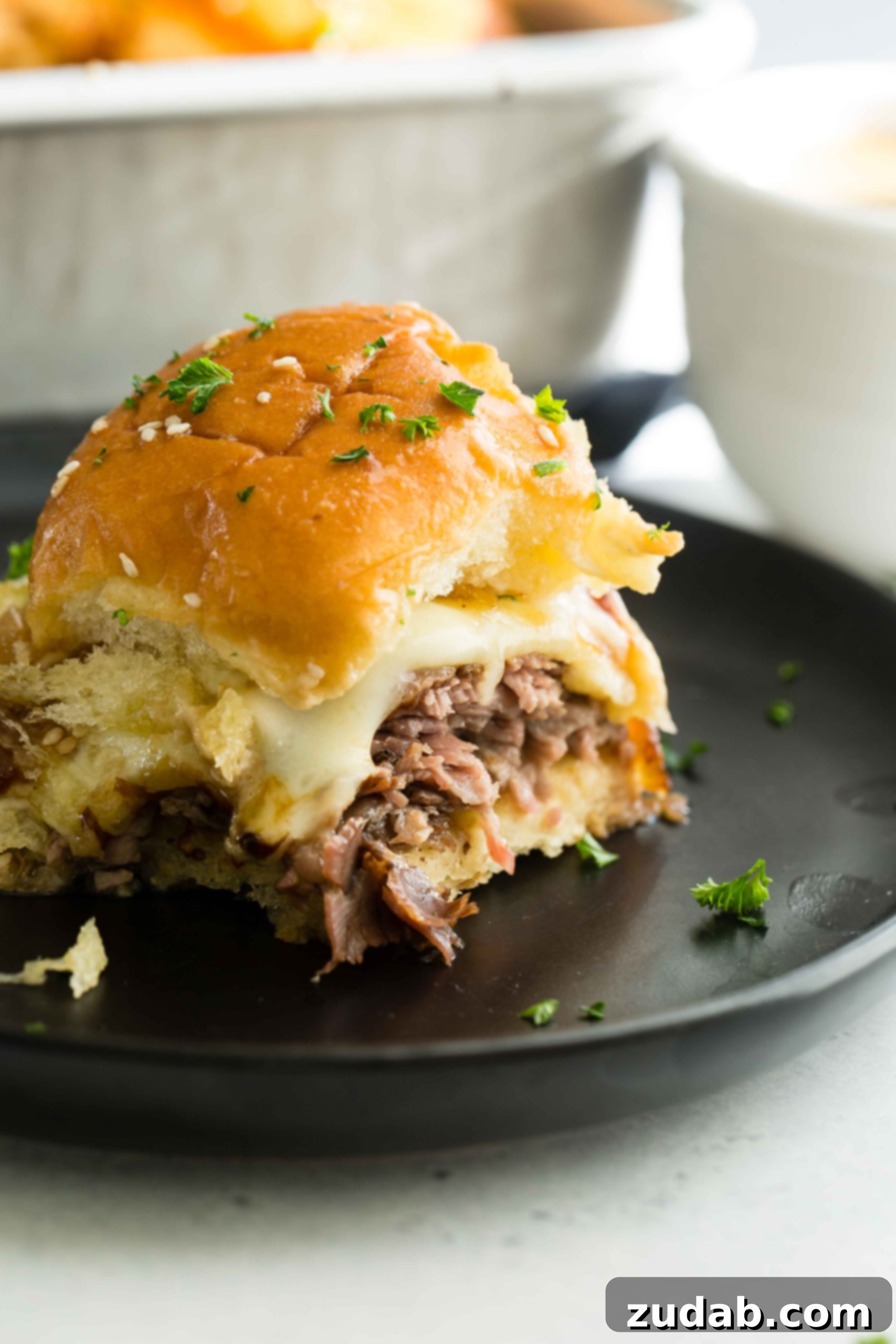 French Dip Sliders 5 A photo of a single french dip slider on a black plate.