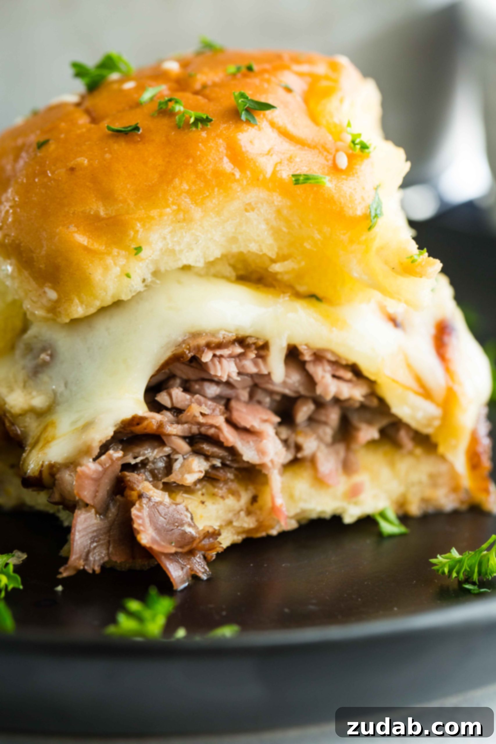 French Dip Sliders 6 A photo of a single french dip slider on a black plate.