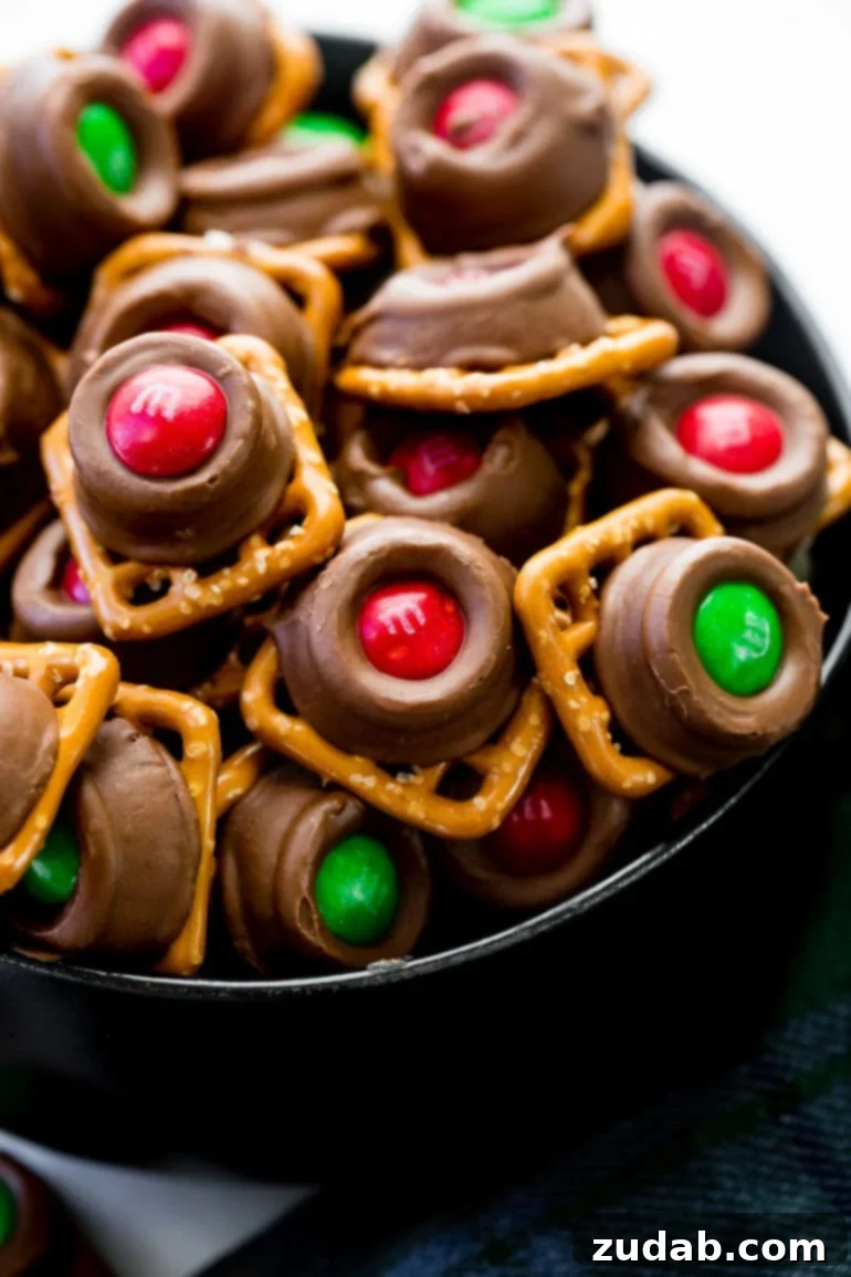 The Ultimate Sweet Salty Rolo Pretzel M and M Treat 2 A festive pile of Rolo Pretzel Bites with M&Ms, featuring square pretzels topped with melted Rolos (caramel-filled milk chocolates) and adorned with colorful Christmas M&Ms.