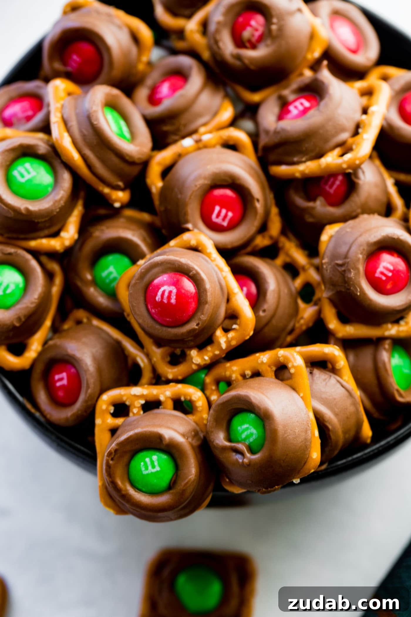 Rolo Pretzels with M&Ms A sleek black bowl brimming with festive Rolo Pretzel Bites with M&Ms, each topped with colorful M&Ms, showcasing the perfect sweet-and-salty holiday treat.