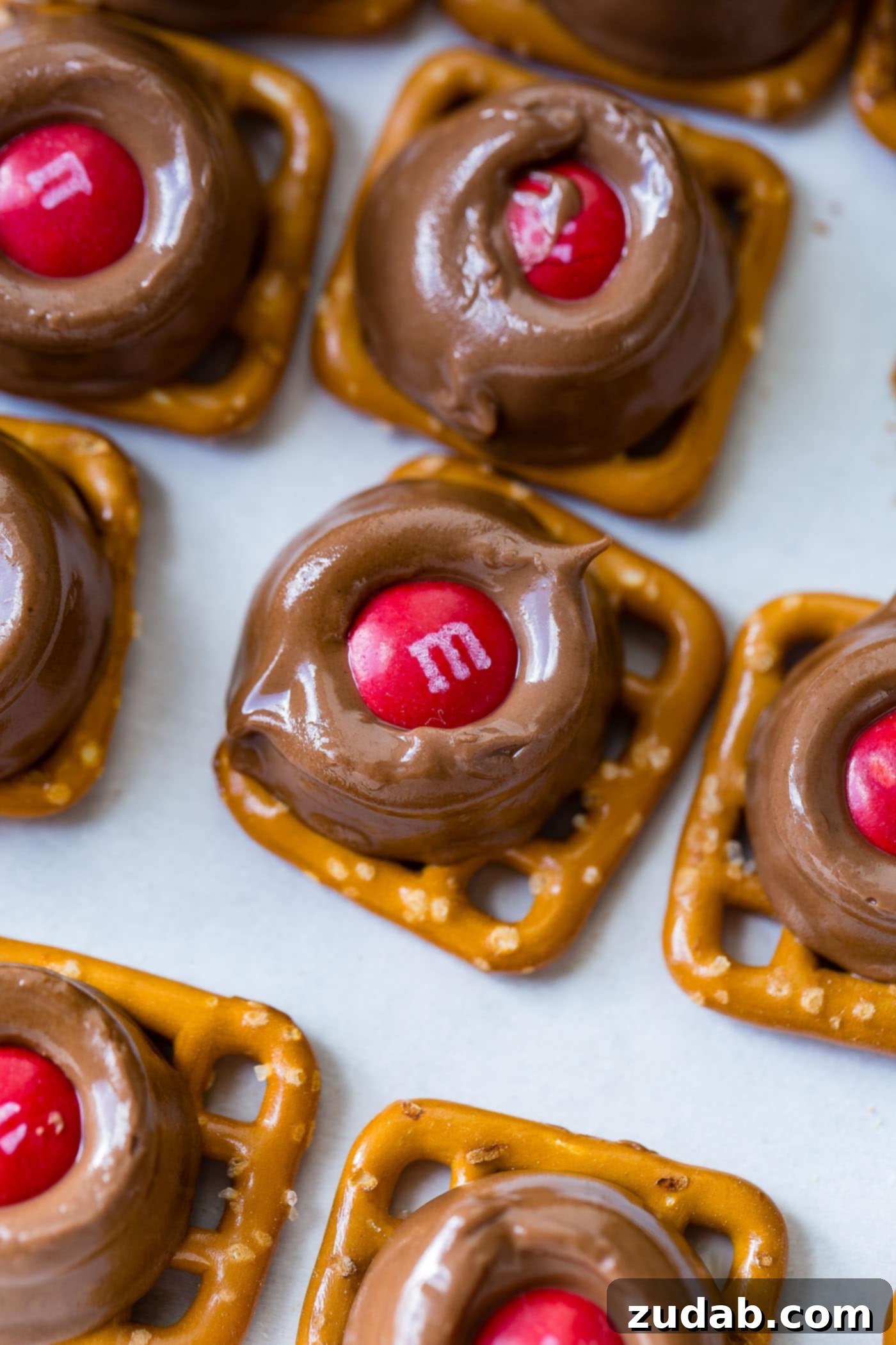 Rolo Pretzels with M&Ms A festive platter with Rolo Pretzel Bites with M&Ms, topped with red and green M&Ms, elegantly arranged on parchment paper for easy serving and a touch of holiday charm.