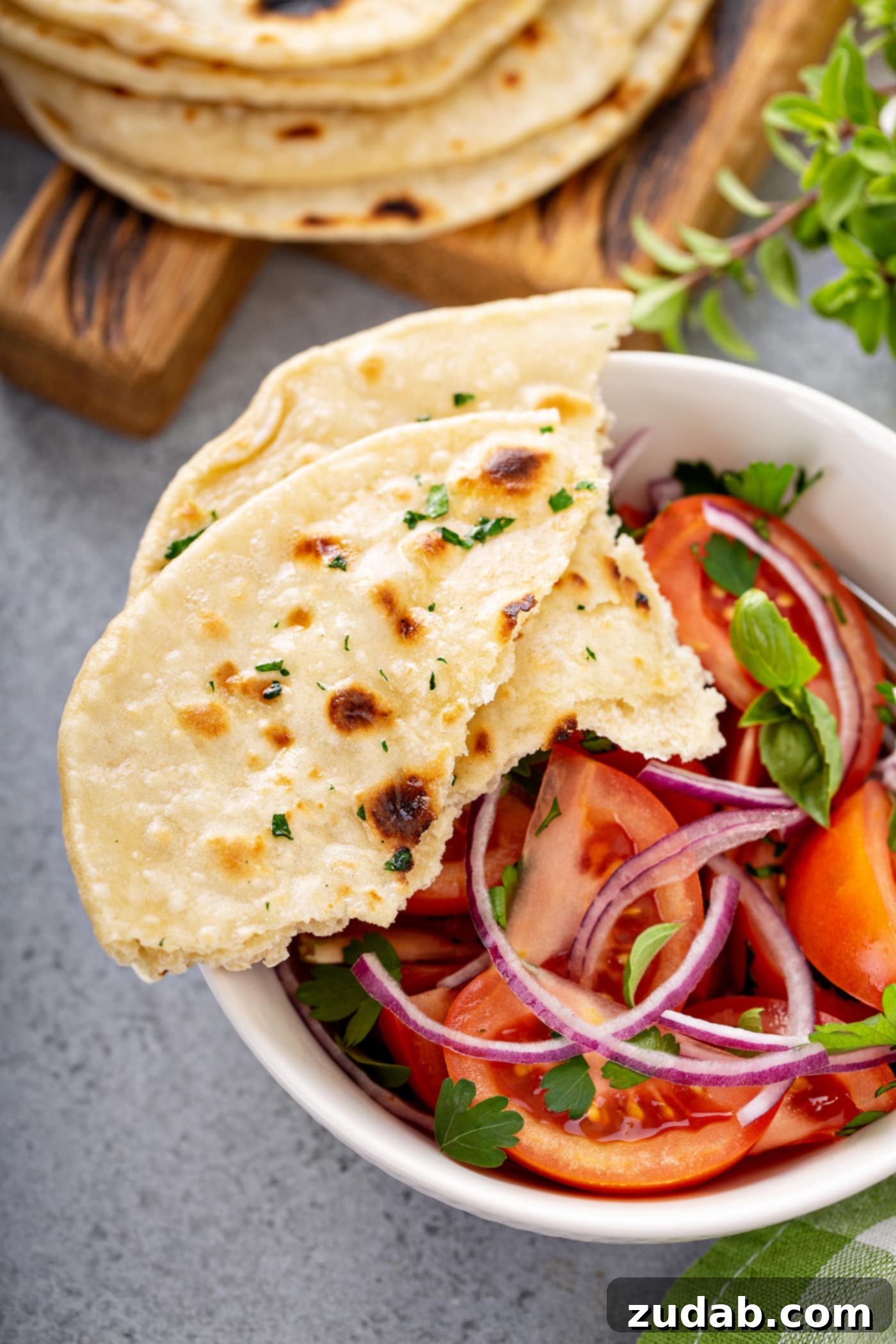 Unleavened Bread A photo of a bowl of fresh tomato and onion salad in a white bowl with torn pieces of unleavened bread sitting on the side of the bowl.