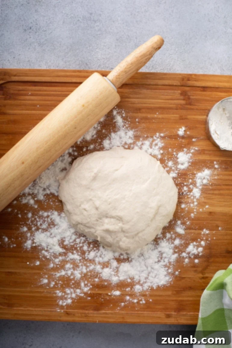 Whip Up Three Ingredient Unleavened Bread 2 A photo of a mound of dough for unleavened bread sitting on a floured wooden cutting board with a wooden rolling pin sitting next to it.