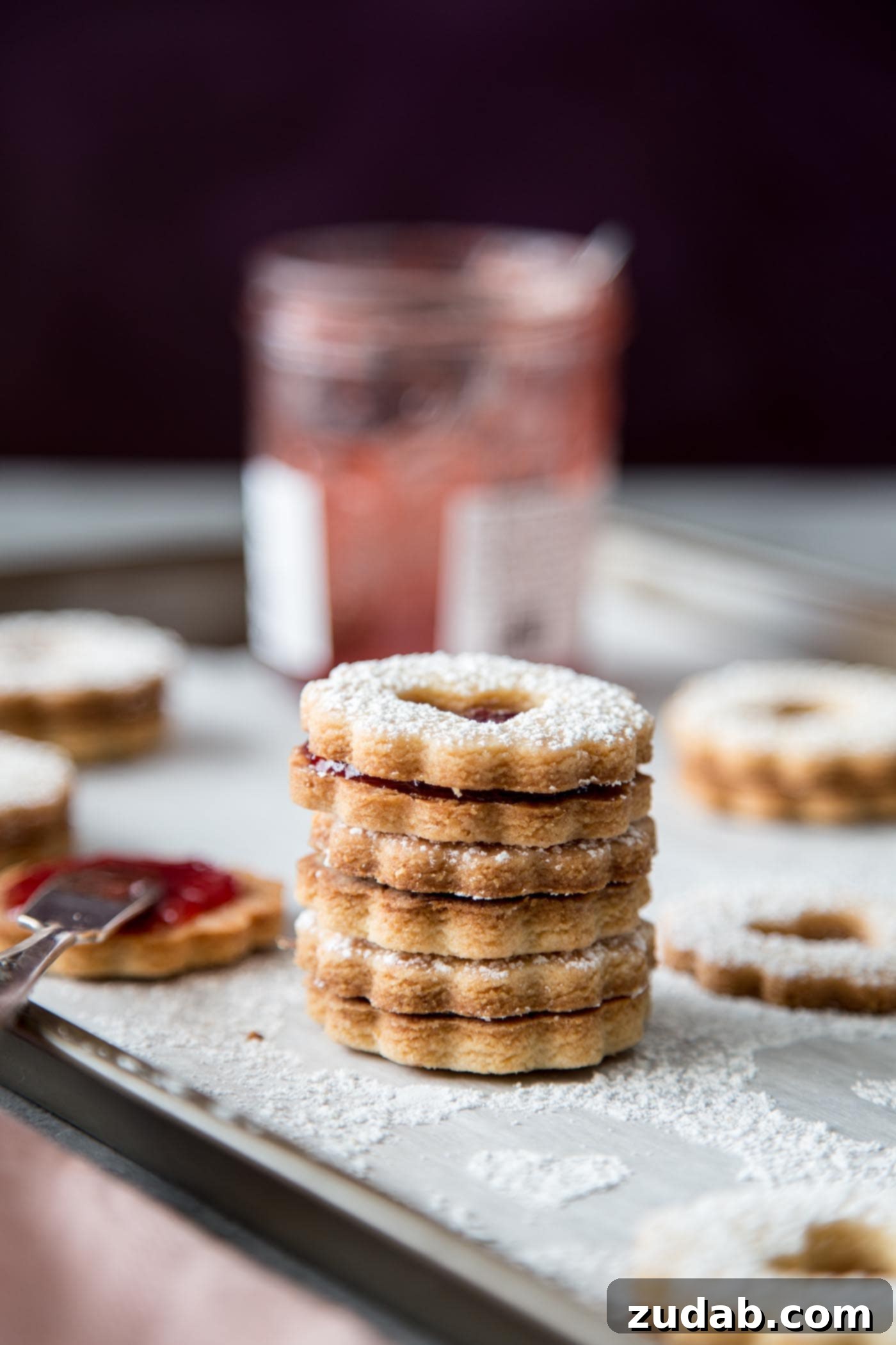 Classic Linzer Cookies 5 A stack of beautifully assembled Linzer cookies with jam showing through heart cutouts