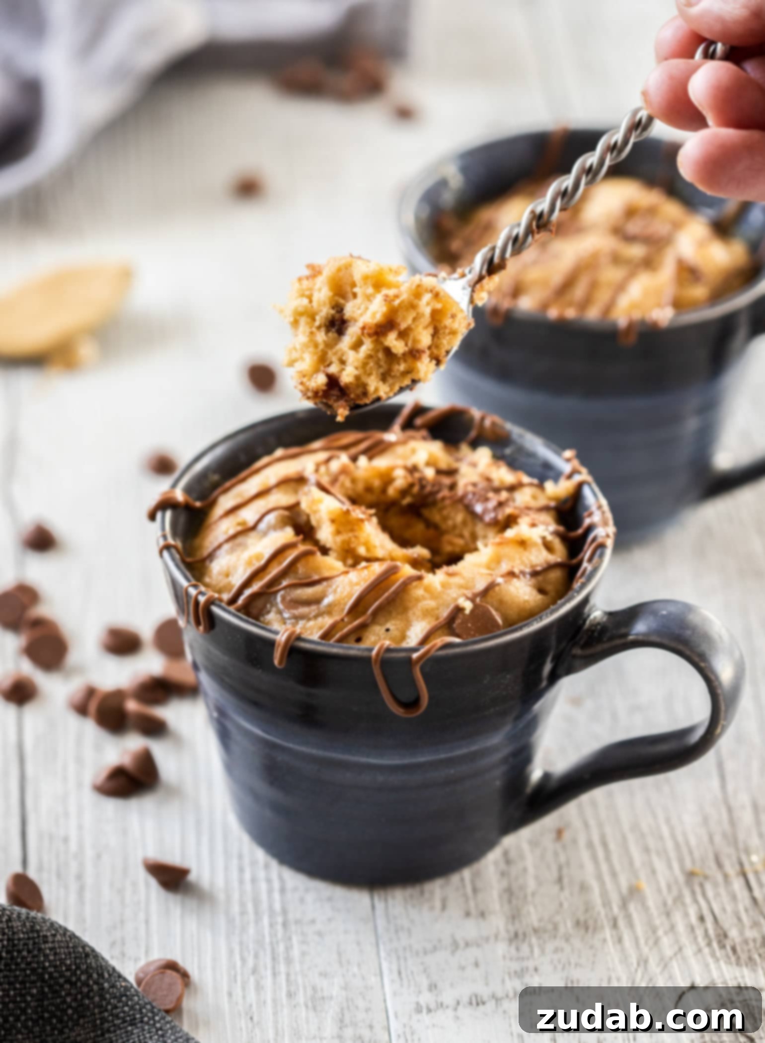 Microwave PB Bliss 5 A spoon scooping cake out of a mug, showing the moist and fluffy texture of the peanut butter mug cake.
