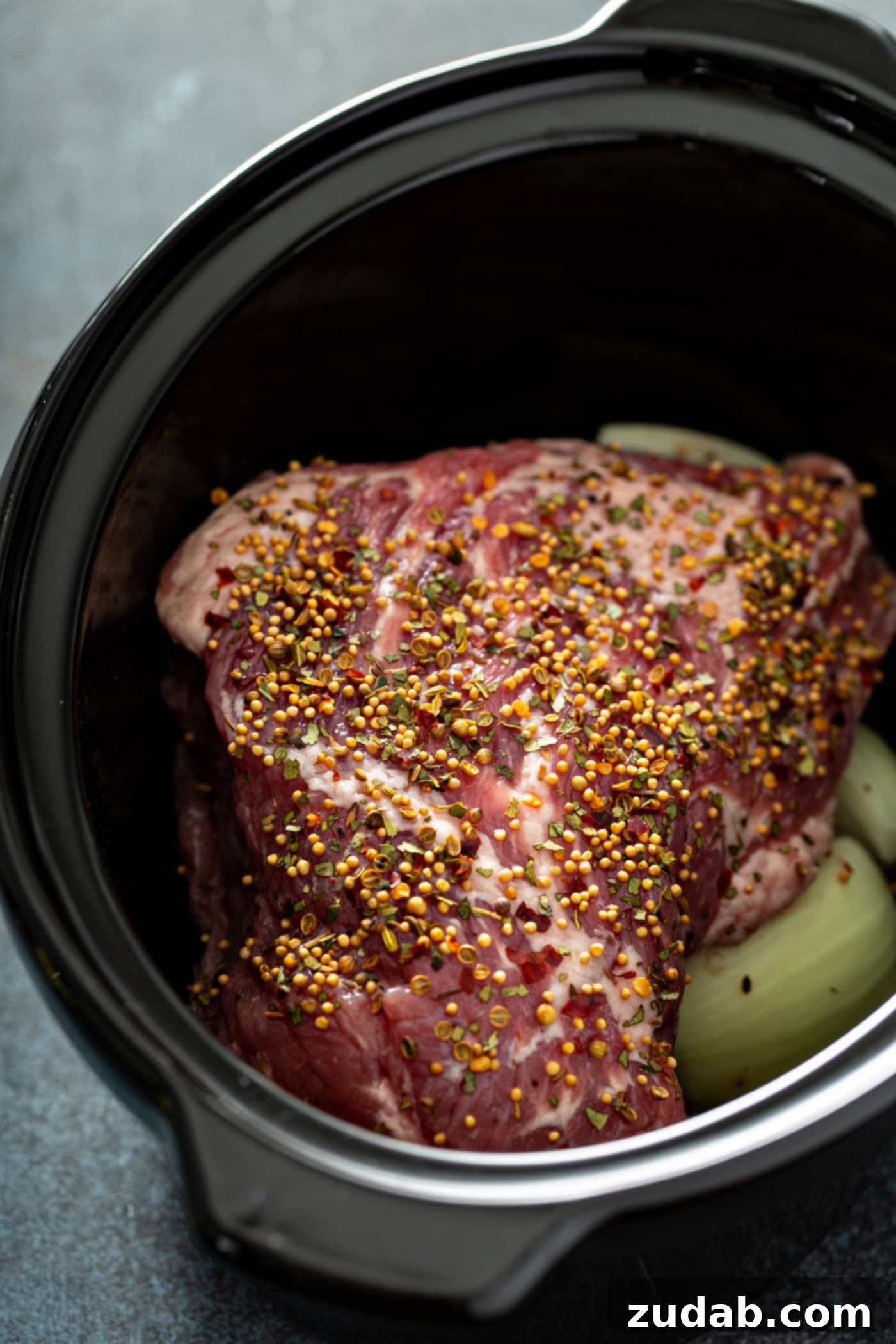 Slow Cooker Corned Beef and Cabbage A slow cooker with potatoes and cabbage in the bottom and a corned beef resting on top.