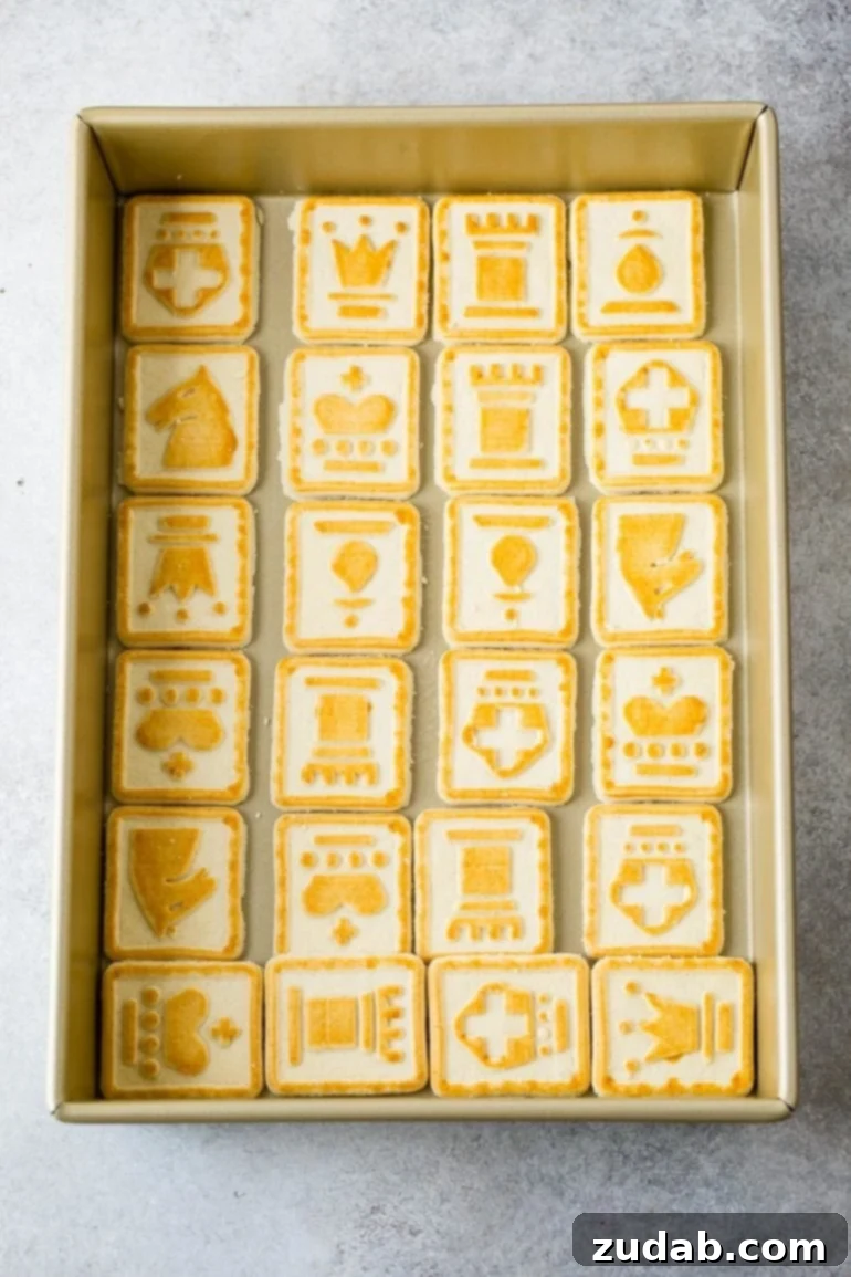 Paula Deen's Legendary Banana Pudding 4 A baking pan meticulously lined with crisp, golden Chessman cookies, each adorned with its distinctive yellow chess symbol. This forms the delicious base of Paula Deen's Not Yo Momma's Banana Pudding, promising a buttery start to a sweet dessert.