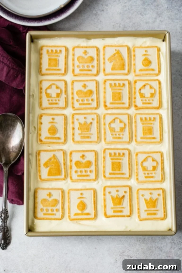 Paula Deen's Legendary Banana Pudding 7 A finished pan of Paula Deen's Not Yo Momma's Banana Pudding, beautifully covered with a final layer of light-colored Chessman cookies, each trimmed with distinctive yellow accents. This top layer is a signature of the dessert, promising a perfect blend of creamy and crisp textures.