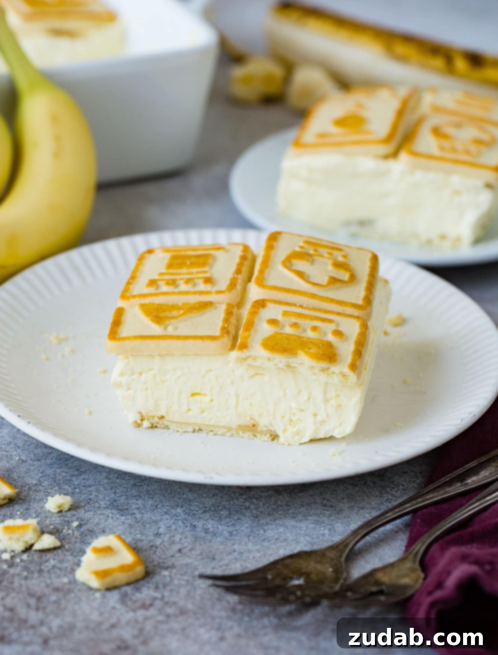 Paula Deen's Legendary Banana Pudding 8 A delightful slice of creamy banana pudding, generously topped with crispy Chessman cookies, sitting elegantly on a plate. The rich, layered texture and inviting aroma make it a perfect dessert for any occasion, promising a satisfyingly sweet experience.