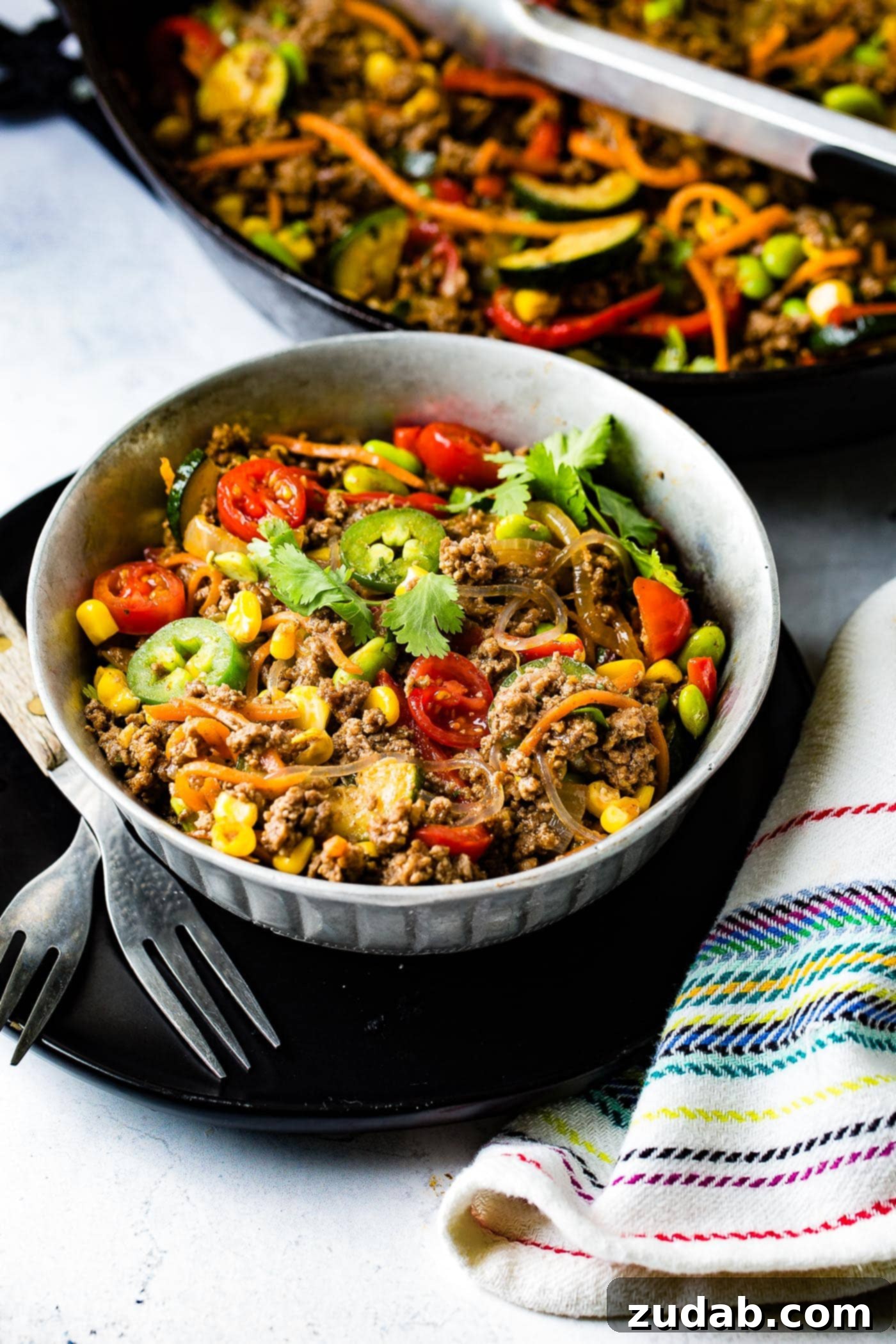 Fiesta Skillet Stir-Fry 2 A vibrant bowl of taco pasta skillet featuring ground beef, corn, zucchini, jalapenos, and tomatoes, all mixed with pasta for a hearty meal.