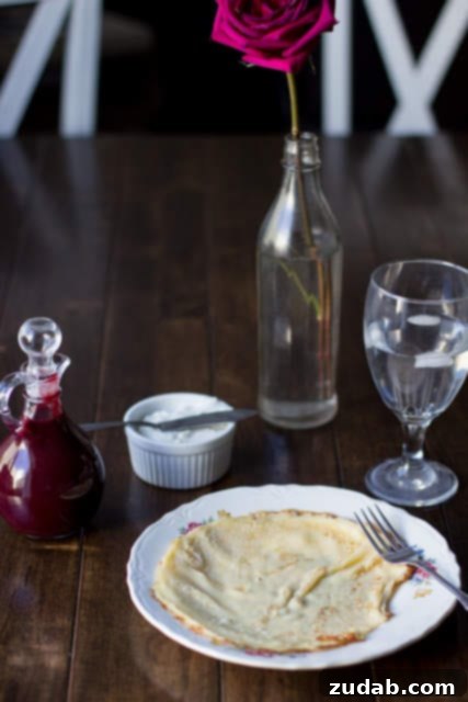 Marionberry Strawberry Syrup served over the most delicious cream filled crepes. #Breakfast at our house is amazing. ohsweetbasil.com Close-up of Berries N' Cream Crepes with Marionberry Strawberry Syrup, showcasing the creamy filling and fresh berry topping.
