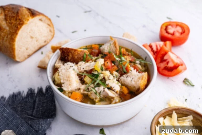 Hearty Instant Pot Italian Chicken Soup 2 A pristine white soup bowl filled with steaming Instant Pot Italian Chicken Soup, generously topped with golden, crusty bread chunks and fresh herbs, ready to be enjoyed.