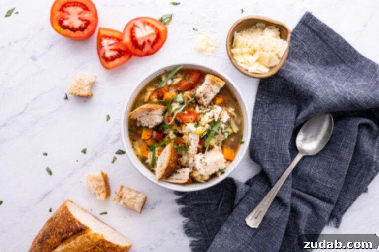 Hearty Instant Pot Italian Chicken Soup 3 A large, rustic bowl of Instant Pot Italian Chicken Soup, accompanied by quartered Roma tomatoes and chunks of golden, crusty bread, presented on a wooden surface.