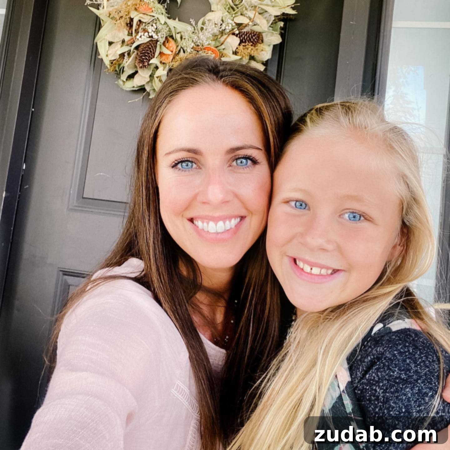 A Mother's Embrace: Creating a Safe Place for Her Child A selfie of a mother and daughter standing outside the front door, sharing a warm embrace and smiles. The setting sun casts a soft glow on their happy faces, symbolizing a moment of loving connection and a safe homecoming.