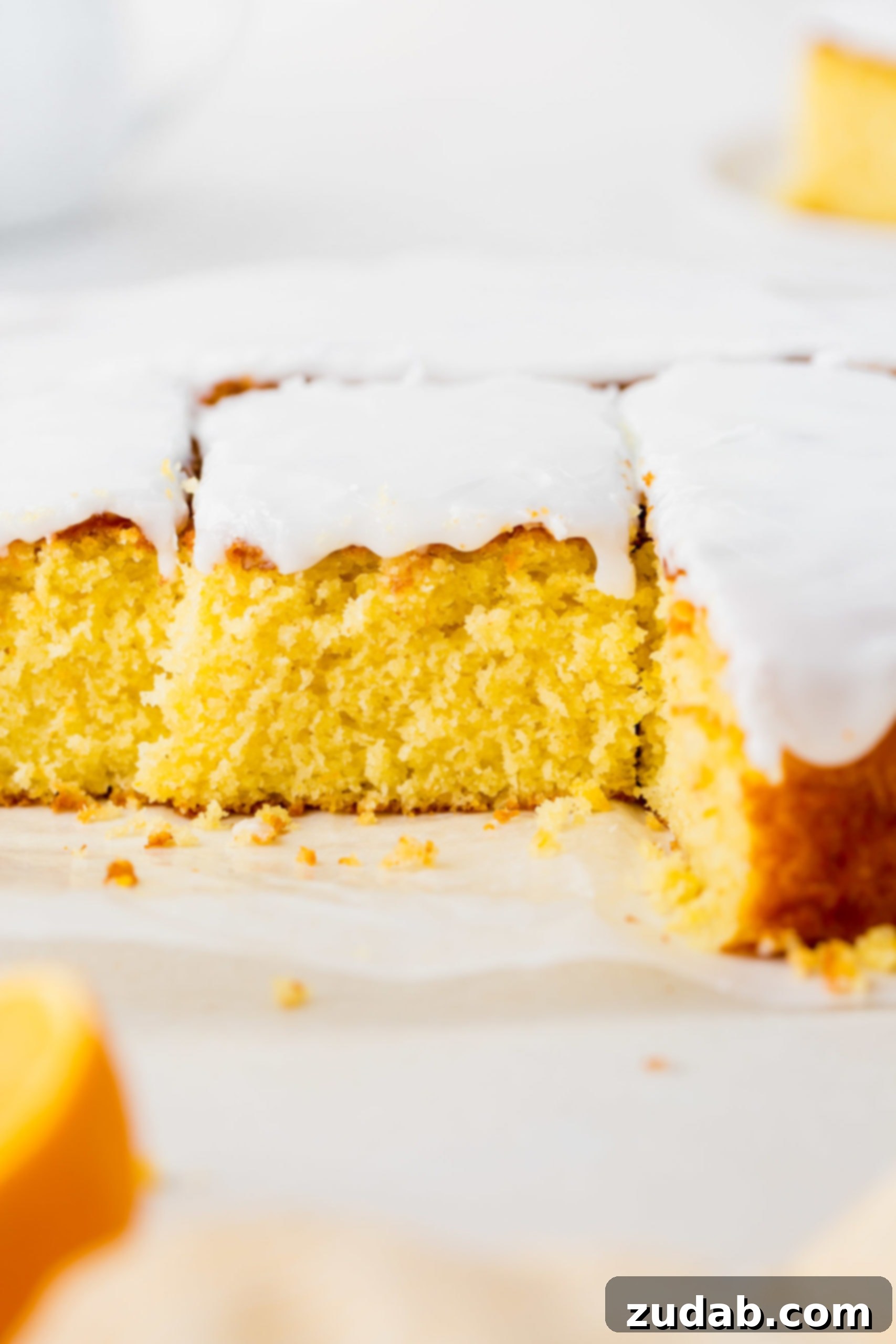 Zesty Glazed Lemon Treat 2 A beautifully cut lemon cake, covered in a luscious white lemon glaze. Several pieces have been removed, highlighting the moist interior, with one middle piece partially cut but still in place.