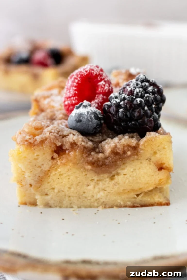A delectable piece of French toast casserole adorned with fresh berries, showcasing a golden-brown crumb topping and a hint of syrup.