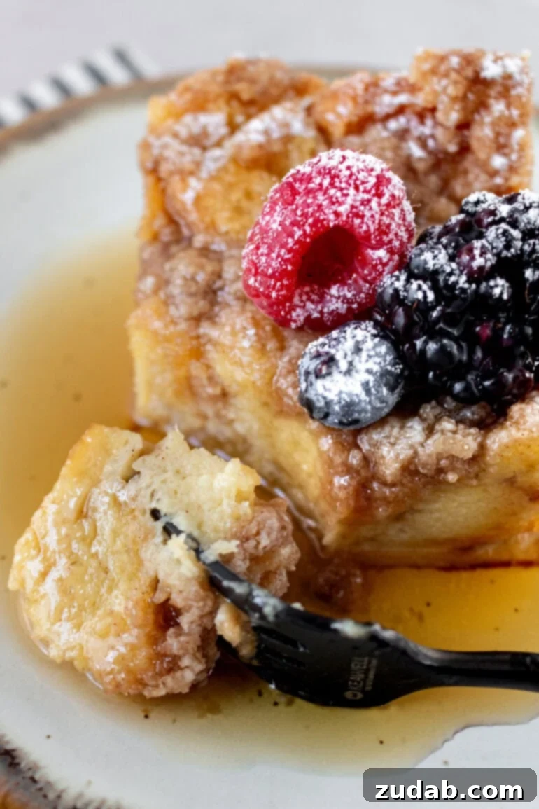 A fork lifting a delicious bite of French toast casserole, showcasing its soft interior and crumb topping.