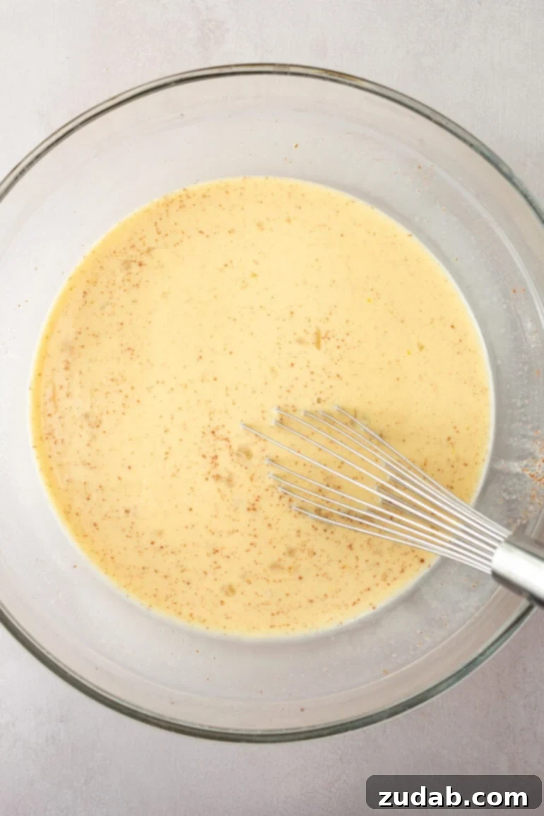 Close-up shot of individual French toast casserole pieces soaking in custard, ready for baking.
