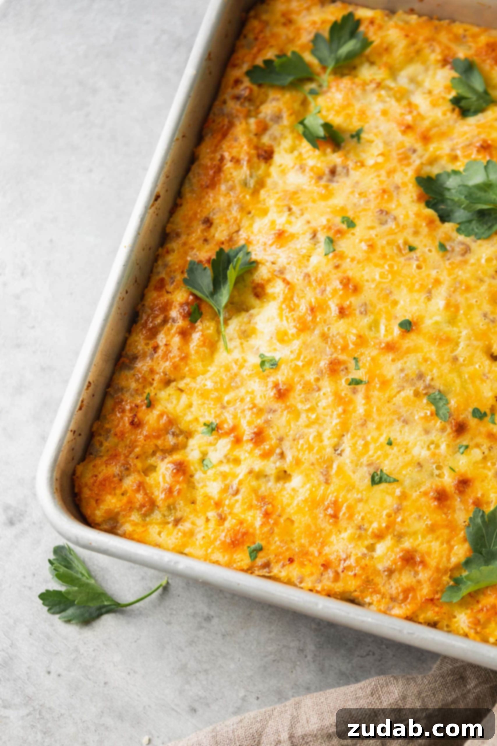 The Most Delicious Sausage Monterey Jack Soufflé A full casserole dish of sausage and cheese soufflé, garnished with a few parsley leaves, ready for serving.