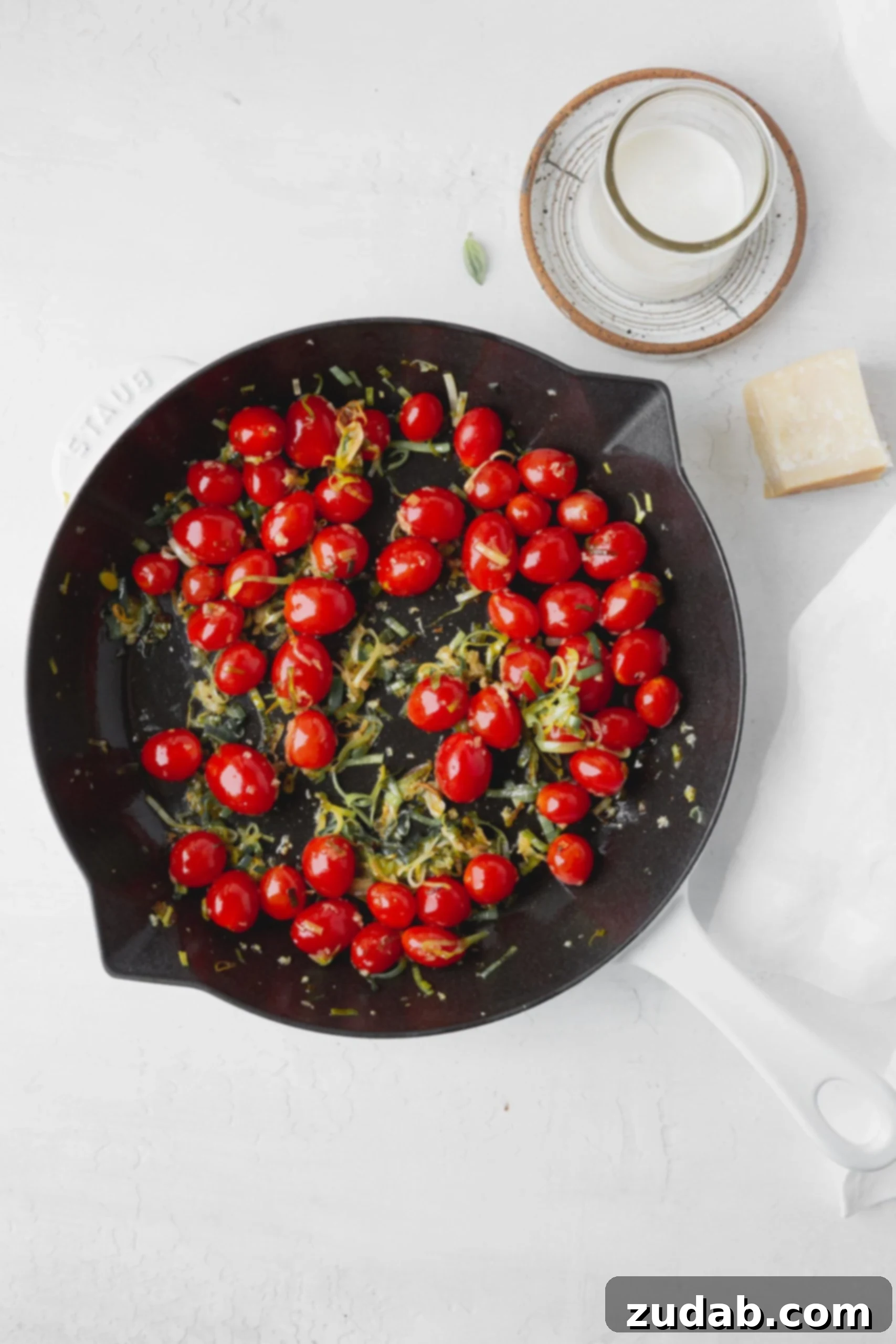 Leeks and Cherry Tomatoes Sautéing A skillet filled with vibrant, sliced leeks and whole cherry tomatoes, ready to be cooked and transformed into a delicious sauce base.