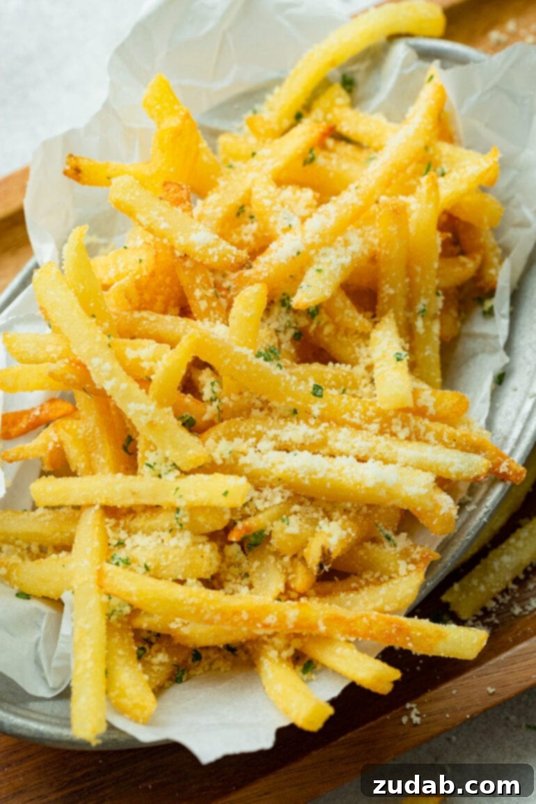 Disneyland's Iconic French Fry Recipe 4 A photo of a generous pile of golden, hot, salty pomme frites, beautifully topped with grated Parmesan cheese and fresh herbs.