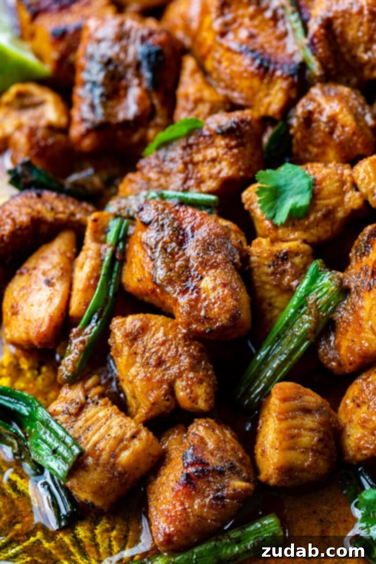 Easy One-Pan 10-Minute Sticky Mexican Chicken 2 A vibrant close-up of perfectly cooked sticky Mexican chicken pieces garnished with fresh green onions and cilantro, ready to be served directly from a pan.