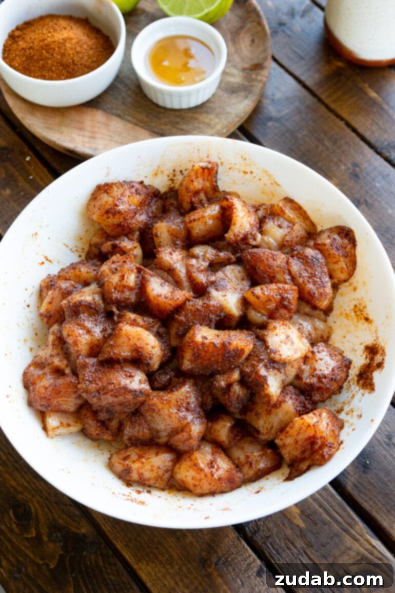 Easy One-Pan 10-Minute Sticky Mexican Chicken 5 A large white serving bowl generously filled with raw, boneless chicken chunks coated in a vibrant homemade taco rub, perfectly seasoned and ready for cooking.