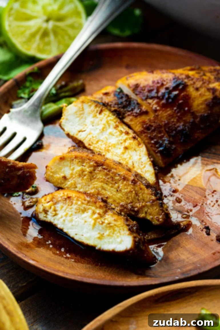 Easy One-Pan 10-Minute Sticky Mexican Chicken 6 A perfectly pan-seared chicken breast, expertly sliced to reveal its incredibly juicy and tender interior, beautifully presented on a rustic wooden board.