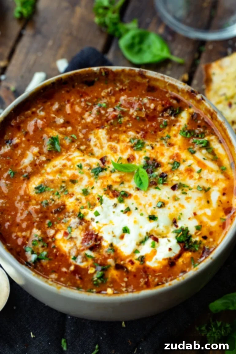 Rustic Italian Beef Chili 2 A large bowl of hearty Italian style beef chili, generously topped with melted mozzarella cheese, a dollop of sour cream, and a sprinkle of fresh chopped herbs, presented invitingly on a rustic wooden surface.