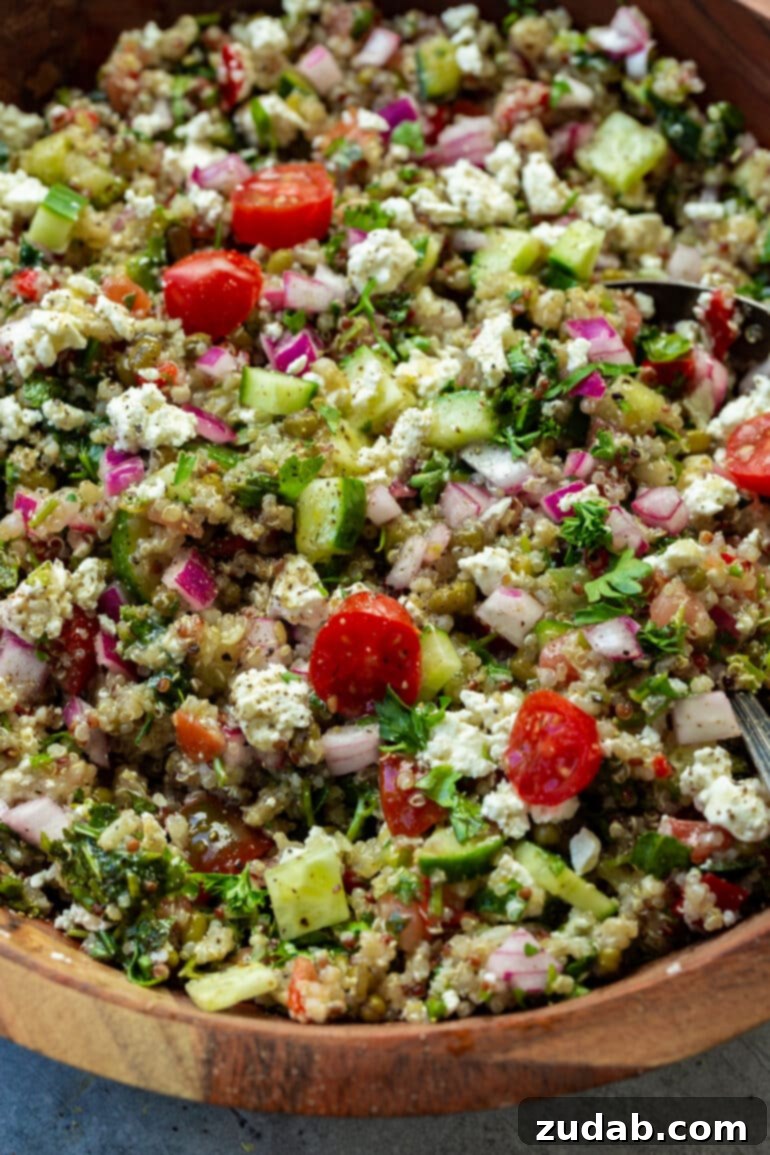 Mediterranean Quinoa Bowl 4 A vibrant Mediterranean Quinoa Bowl, beautifully composed with crisp cucumbers, ripe tomatoes, crumbled feta, thinly sliced red onions, and aromatic fresh herbs, all generously drizzled with a homemade dressing.