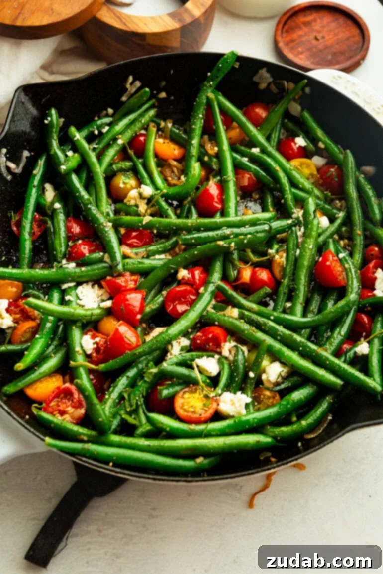 Garlic Green Bean and Cherry Tomato Sauté 3 A pan full of brightly colored green beans and multi-colored cherry tomatoes, lightly topped with fresh herbs and crumbled cheese.