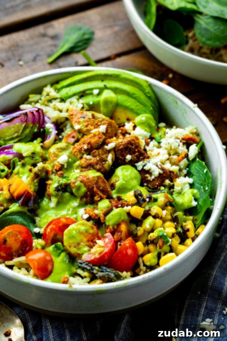 Weekly Meal Planner September 11 to 17 3 A white bowl brimming with cilantro-lime rice, sticky Mexican chicken, grilled corn, diced tomatoes, sliced avocado, red onions, and a vibrant green creamy avocado dressing.
