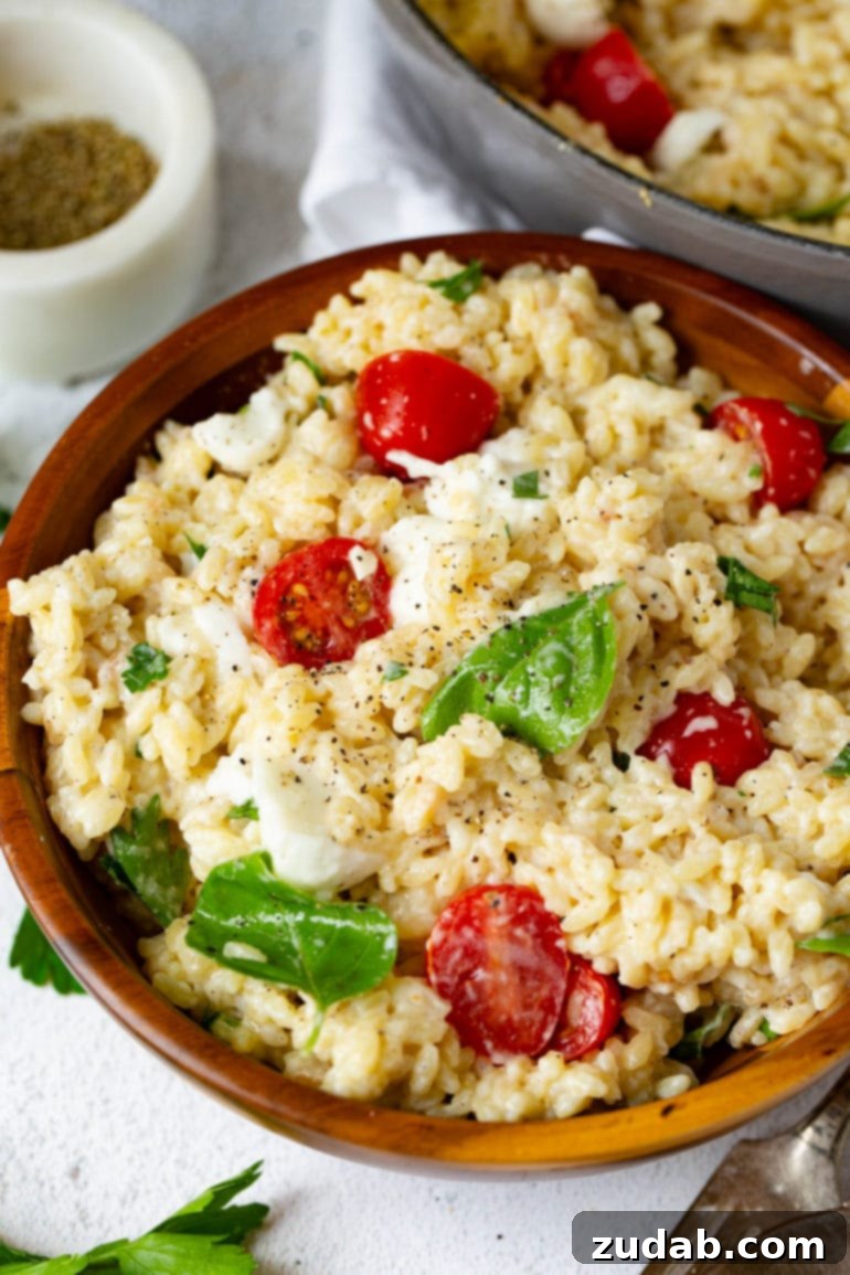 Weekly Meal Planner September 11 to 17 4 A bowl of fresh Caprese Orzo Salad featuring small pasta, ripe tomatoes, creamy mozzarella chunks, and vibrant basil leaves, with fresh ground pepper and parsley nearby.