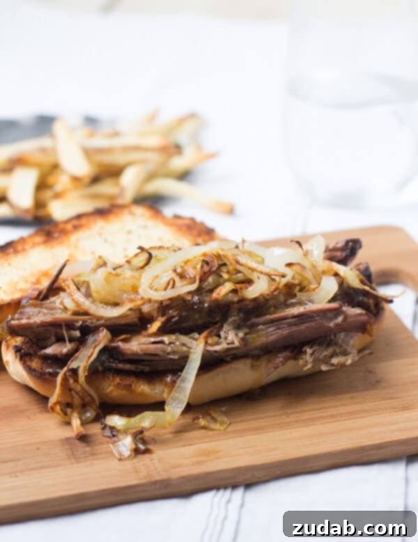 This pot roast sandwich is going to have husbands everywhere proposing all over again. Mark. My. Words. It's just that good. Homemade Pot Roast sandwich with caramelized onions on a wooden board.