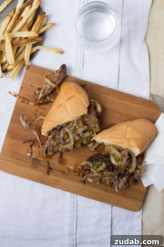 This pot roast sandwich is going to have husbands everywhere proposing all over again. Mark. My. Words. It's just that good. Pot Roast sandwich cut in half on a wooden board on top of a white table cloth next to french fries.