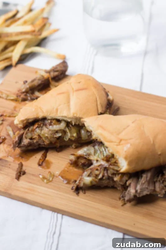 This pot roast sandwich is going to have husbands everywhere proposing all over again. Mark. My. Words. It's just that good. Easy Pot Roast sandwich cut in half on a wooden board on top of a white table cloth.