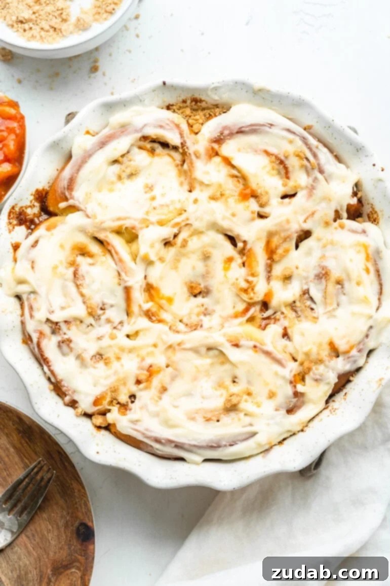 Delicious Peach Cobbler Cinnamon Rolls 3 a photo of a circular baking dish full of frosted golden peach cobbler cinnamon rolls