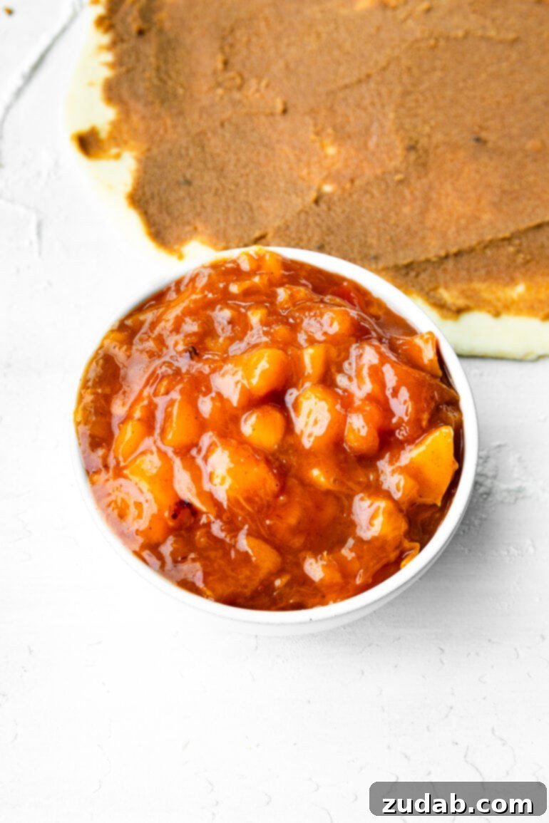 Delicious Peach Cobbler Cinnamon Rolls 6 a photo of a small bowl of peach jam with chunks of fresh peaches in it