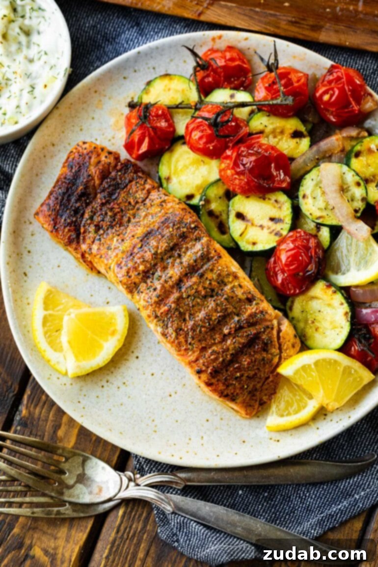 The Ultimate Guide to Perfectly Grilled Salmon 3 A beautifully grilled, seasoned salmon fillet rests on a dinner plate, accompanied by vibrant grilled vegetables and bright lemon wedges, ready to be served. This image showcases a healthy, flavorful, and easy dinner option.