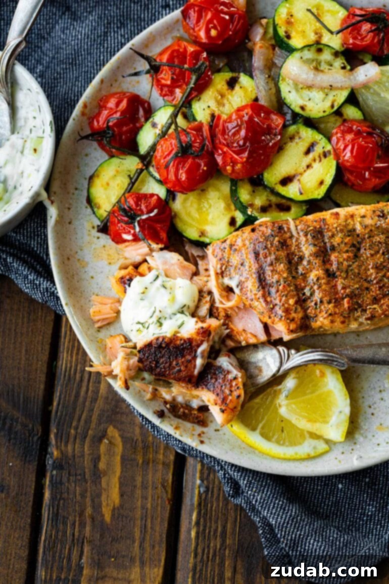The Ultimate Guide to Perfectly Grilled Salmon 6 A close-up of a perfectly grilled salmon fillet, with flakes visible where a fork has been inserted, signifying its tender and moist texture. It's accompanied by grilled vegetables, highlighting a balanced and healthy meal.