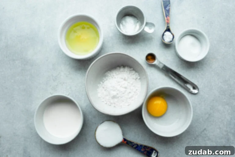 Pillowy Soft Japanese Pancakes 4 A photo of all the ingredients needed for Japanese pancakes, neatly arranged in separate small bowls, including egg yolk, egg whites, flour, sugar, and vanilla.