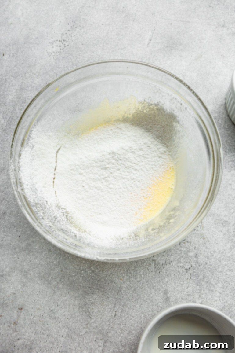 Pillowy Soft Japanese Pancakes 6 A photo of Japanese cloud pancake batter in a large glass bowl with sifted flour added, showing the light consistency.